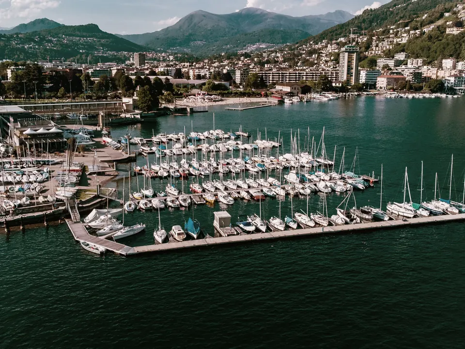 Lugano dall'alto: il porto turistico sul lago, la città e le montagne