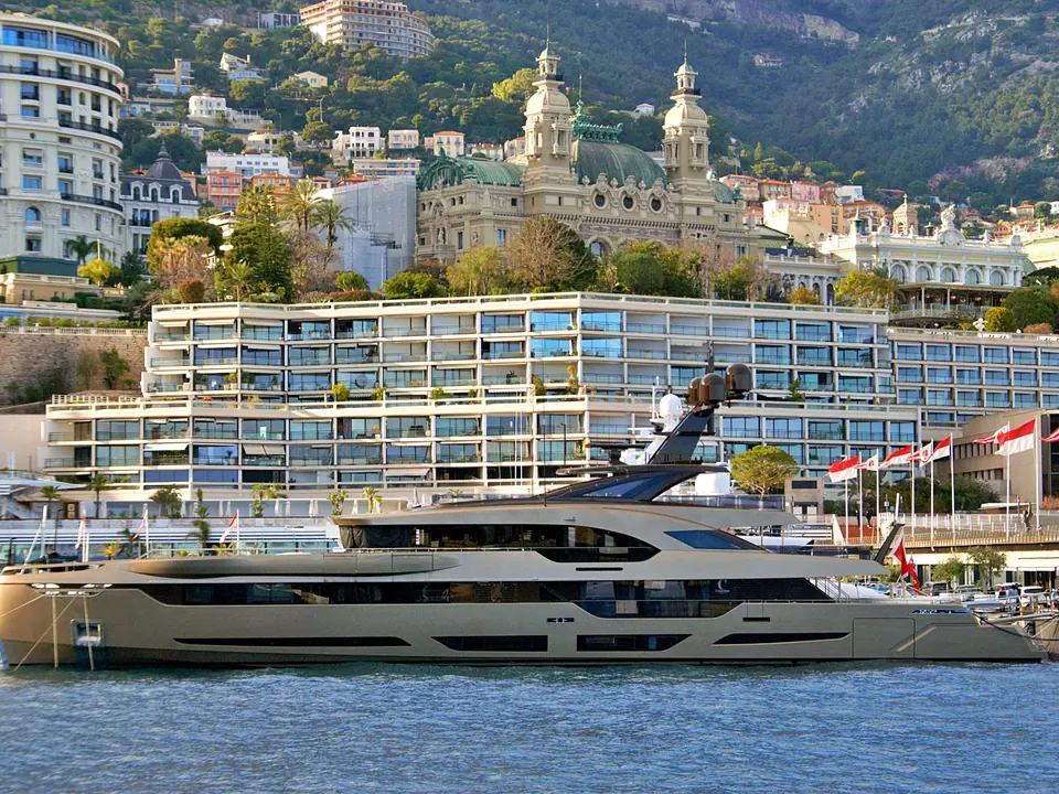Il porto di Monaco con uno yacht all'ormeggio e, sulla collina, Monte-Carlo